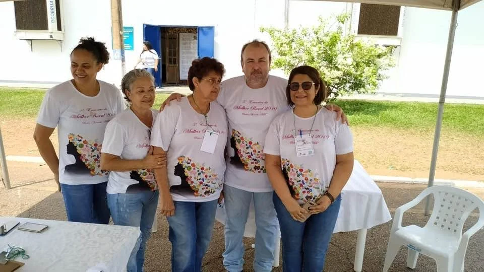 Alcino acompanhado de quatro pessoas em um espaço coberto